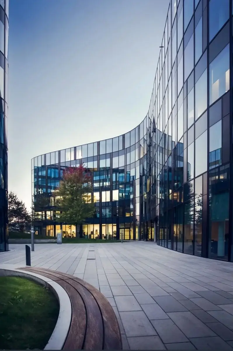 Modern glass office building beside a paved plaza